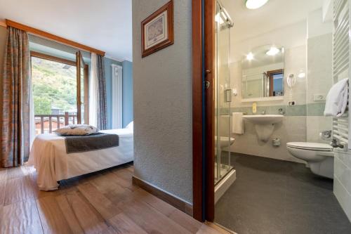a bathroom with a bed and a sink and a toilet at Hotel Du Glacier in La Thuile