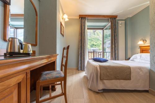 una camera con letto e scrivania con specchio di Hotel Du Glacier a La Thuile