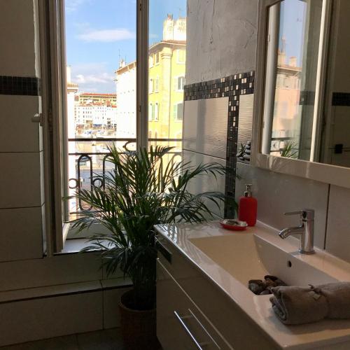 une salle de bain avec un lavabo et une grande fenêtre dans l'établissement Le cocon de Louise-Vieux Port, à Marseille