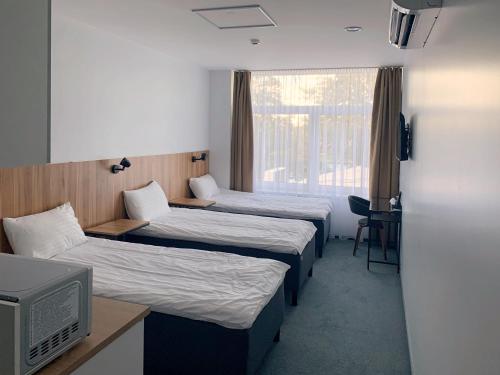 a hotel room with three beds and a television at Muontis in &Scaron;ilalė