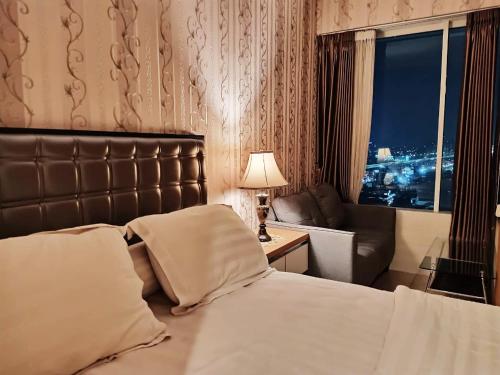 um quarto de hotel com uma cama e uma cadeira e uma janela em Grand Kamala Lagoon by 21 Room Netflix em Bekasi