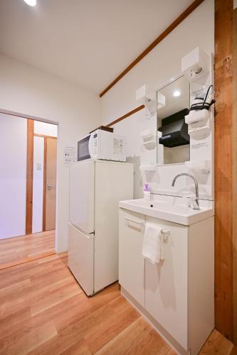 a white kitchen with a sink and a refrigerator at 鴨川 栄の屋 Kamo River Machiya Halo House in Kyoto