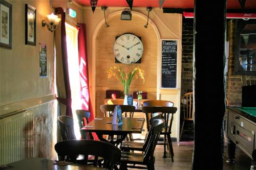 un restaurante con un reloj en la pared y mesas en The White Horse, en Beyton