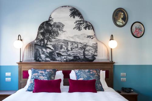 Hotel Indigo Verona - Grand Hotel Des Arts, an IHG Hotel في فيرونا: غرفة نوم مع لوحة كبيرة فوق سرير مع وسائد حمراء