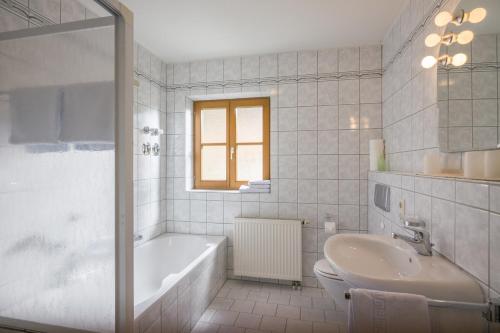 Baño blanco con bañera y lavamanos en Christophenhof, en Oberaudorf