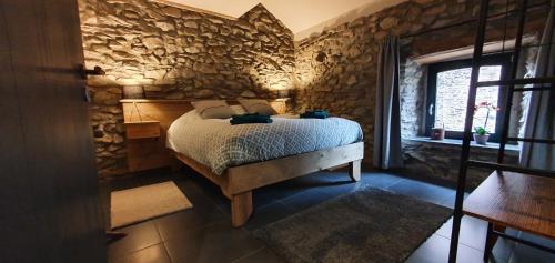 ein Schlafzimmer mit einem Bett und einer Steinmauer in der Unterkunft O Près de la Lienne, maison de campagne de charme, accord parfait entre confort et authenticité in Lierneux