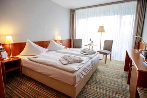 Habitación de hotel con cama y silla en Mercure Hotel Riesa Dresden Elbland en Riesa