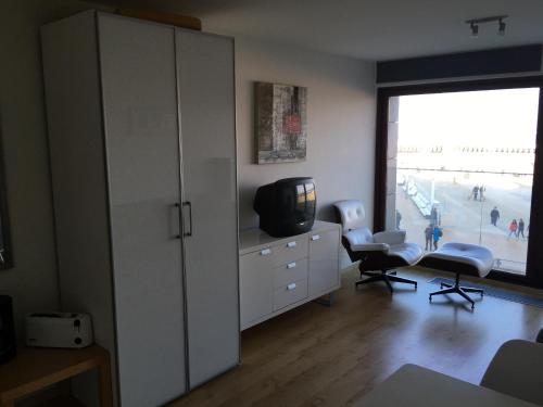 a living room with a tv and a cabinet and chairs at prachtige studio met havenzicht in Ostend
