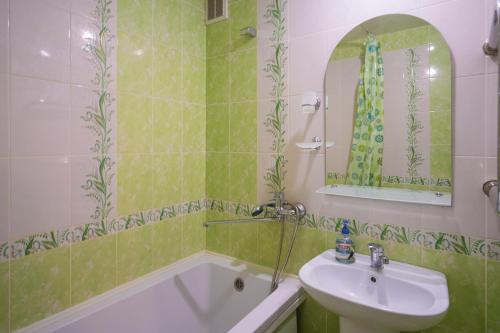 y baño de azulejos verdes con lavabo y bañera. en Апартаменты на Бирули от ApartmentCity, en Mogilev