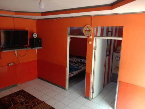 una camera con una parete arancione, una TV e una piccola stanza di Pondok orange ciwidey a Bandung