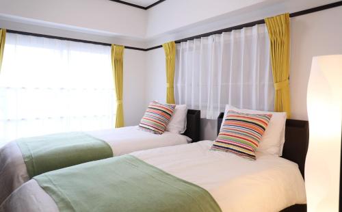 two beds sitting next to a window in a bedroom at ケイアイコンホテルズ 池下 in Chikusachō