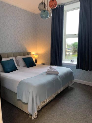 a bedroom with a bed with blue pillows and a window at No. 1 Charlotte Street in Port Ellen
