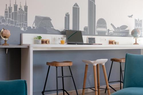 a bar with stools and a laptop on a counter at Kyriad Hotel Lyon Givors in Givors