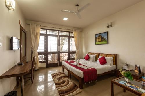 a bedroom with a bed and a table and a desk at KSTDC Hotel Mayura Pine Top Nandi Hills in Nandi