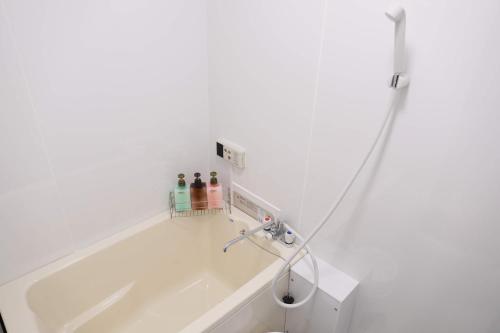 a white bathroom with a tub and a sink at ケイアイコンホテルズ 池下 in Chikusachō