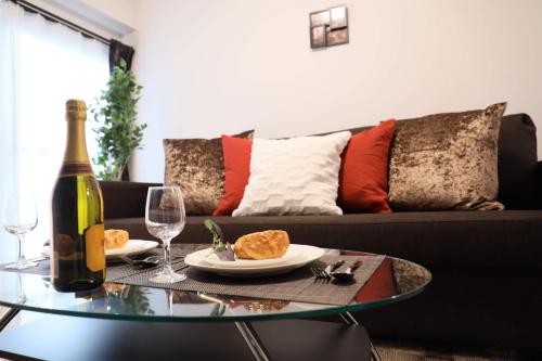 a living room with a bottle of wine and a glass table at ケイアイコンホテルズ 池下 in Chikusachō