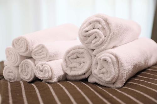 a pile of towels sitting on top of a bed at ケイアイコンホテルズ 池下 in Chikusachō