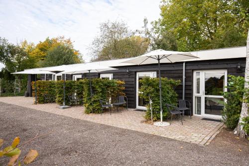 a black building with a patio with chairs and an umbrella at Herberg de Appelgaard in Barneveld