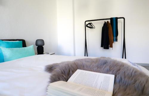ein Schlafzimmer mit einem Bett mit einem Buch und einem Kleiderständer in der Unterkunft *NEU* Zentral (nur 5min bis zur Innerstadt) *Netflix & Amazon TV* in Magdeburg