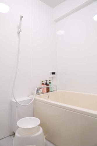 a white bathroom with a toilet and a bath tub at ケイアイコンホテルズ 池下 in Chikusachō