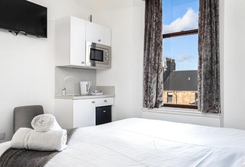 a bedroom with a white bed and a white microwave at Kelpies Serviced Apartments in Falkirk