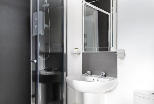 a bathroom with a sink and a shower with a mirror at Kelpies Serviced Apartments in Falkirk