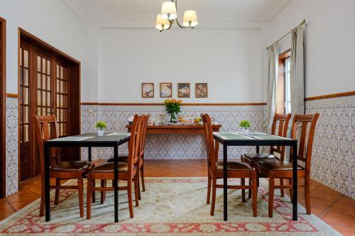een eetkamer met 2 zwarte tafels en houten stoelen bij Classico Guesthouse in Vila Nova de Gaia