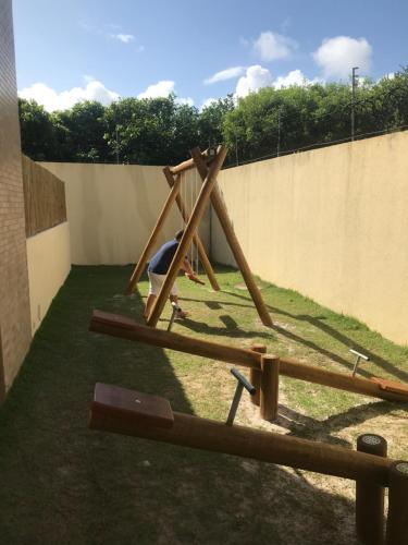 a wooden swing set in a yard next to a wall at Imbassai Summer Flats Village in Imbassai