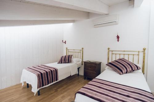 two beds in a room with white walls and wooden floors at Leano Agriresort in Piazza Armerina