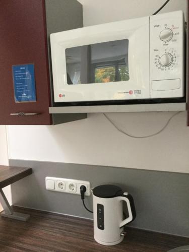 a microwave above a coffee pot in a kitchen at Airport Park Hotel MUC in Hallbergmoos