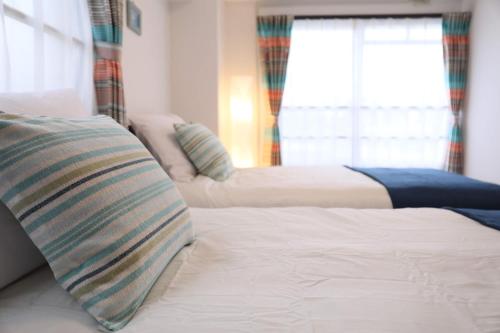 a bedroom with two beds and a window at ケイアイコンホテルズ 池下 in Chikusachō