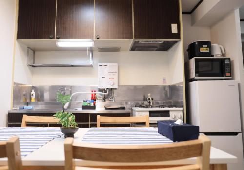 a kitchen with a table and a white refrigerator at ケイアイコンホテルズ 池下 in Chikusachō