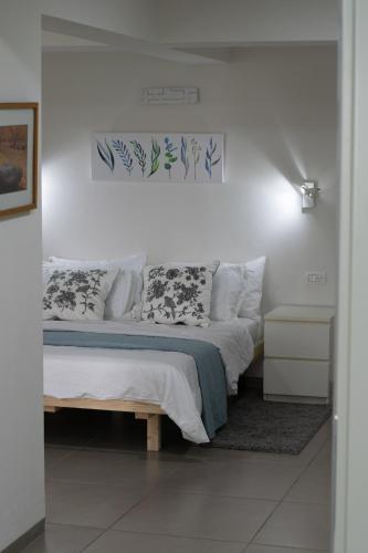 a bedroom with a bed with white sheets and pillows at הבית של סתיו in Rosh Pinna
