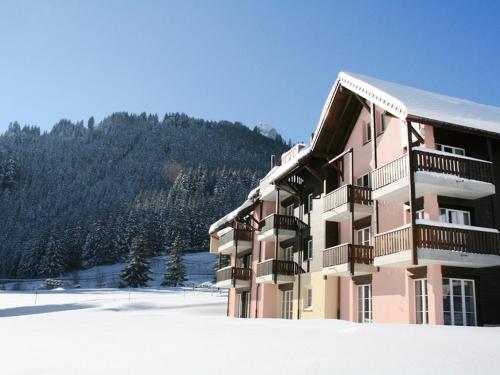 a pink building with snow in front of a mountain at Apartment Andromède 3-pièces A34 by Interhome in Moleson