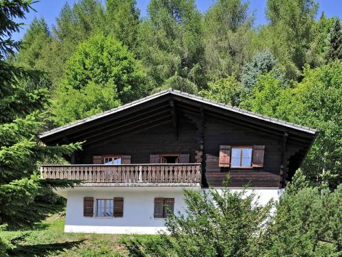 a wooden house with a balcony in the woods at Chalet Chalet le Chamois by Interhome in Moleson