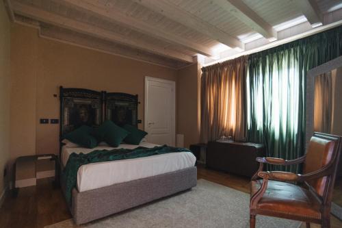 a bedroom with a bed with green curtains and a chair at Leano Agriresort in Piazza Armerina