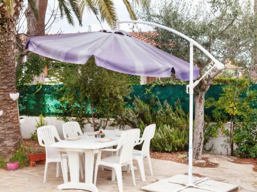 レスカラにあるHoliday Home La Bahia by Interhomeの紫の傘下の白いテーブルと椅子