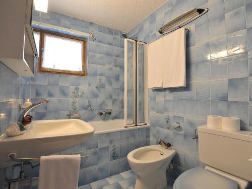 a blue tiled bathroom with a toilet and a sink at Chalet Mountain View by Interhome in Moleson