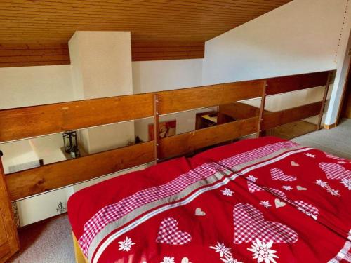 a bed with a red and white blanket on it at Apartment Chez-Nous by Interhome in Gstaad