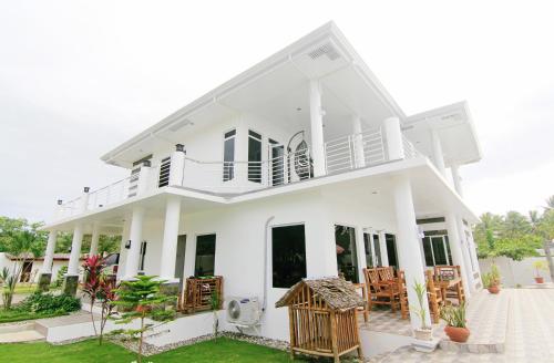 a white house with chairs in the yard at J&R Residence in Anda