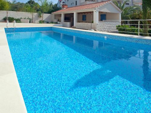 a swimming pool with blue water in front of a house at Apartment Villa 2 Pools-1 by Interhome in Sutivan