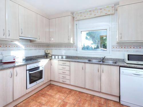 a kitchen with white cabinets and a window at Holiday Home Eva by Interhome in L'Escala