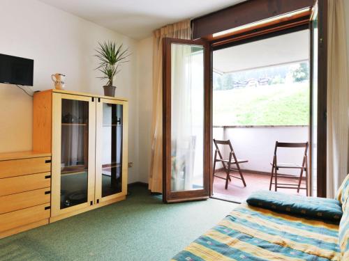 ein Wohnzimmer mit einer Glasschiebetür und einem TV in der Unterkunft Apartment Enrosadira-5 by Interhome in Alba di Canazei