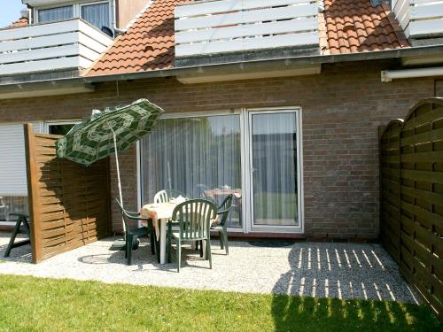 eine Terrasse mit einem Tisch mit Stühlen und einem Sonnenschirm in der Unterkunft Apartment Kluntje by Interhome in Norddeich