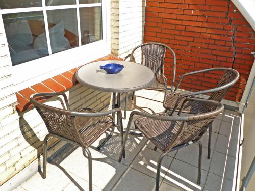 uma mesa com quatro cadeiras e uma tigela azul em Apartment Krabbe by Interhome em Norddeich