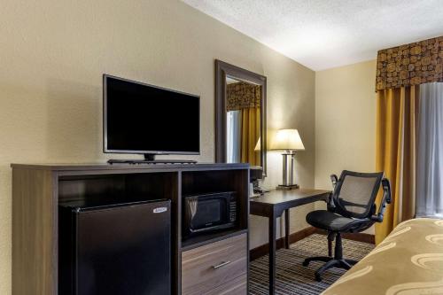 a hotel room with a television and a desk with a chair at Quality Inn & Suites - Greensboro-High Point in Greensboro