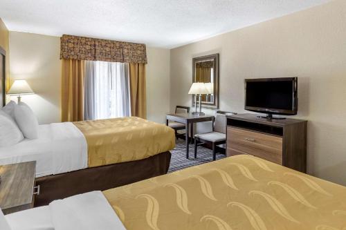 a hotel room with two beds and a flat screen tv at Quality Inn & Suites - Greensboro-High Point in Greensboro