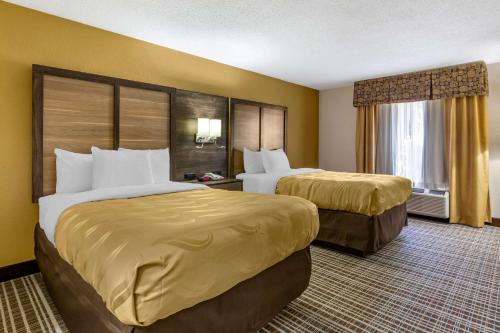 a hotel room with two beds and a window at Quality Inn & Suites - Greensboro-High Point in Greensboro