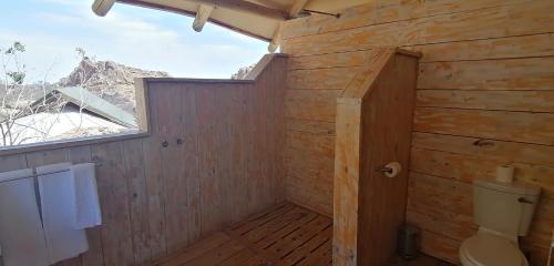 a wooden bathroom with a toilet and a window at Ondudu Safari Lodge in Omaruru