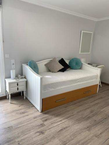 1 dormitorio con cama blanca y suelo de madera en Hostal Antolín, en Redondela